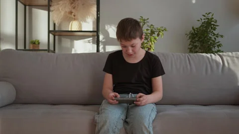 Boy Playing Mobile Game on Sofa Stock Footage 335477735