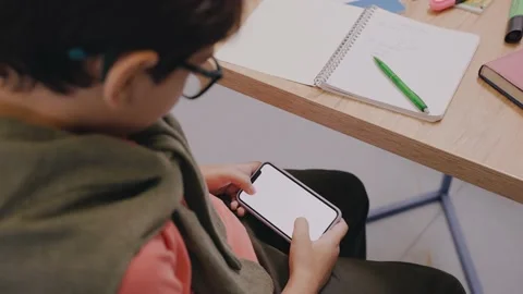 Boy is playing mobile games at the break sitting at the desk Video stock 162739475