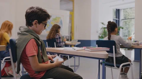Boy is playing mobile games under the desk during lesson and getting caught 스톡 동영상 162735879