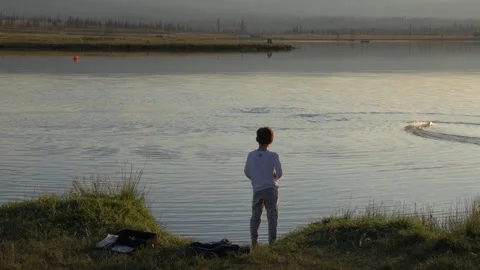 A boy playing with model boat on lake. 库存影片 248942653