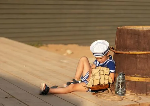 A boy is playing with a model of a sailing ship. Stock Photos