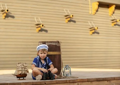 A boy is playing with a model of a sailing ship. Stock Photos