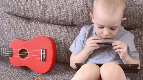 Boy playing musical instruments harmonica, ukulele Video stock 172538031