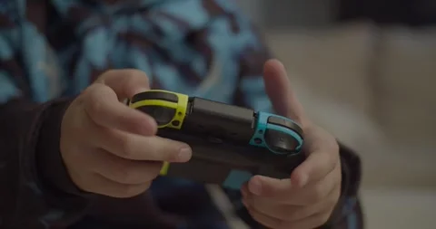 Boy playing with Nintendo Switch controller - Pan Left camera movement Stock-Footage 253741199