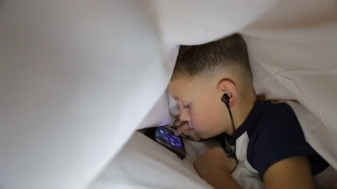 The boy is playing not the phone under the blanket Stock Footage 81564010