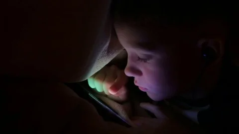 The boy is playing not the phone under the blanket Stock Footage 81564032
