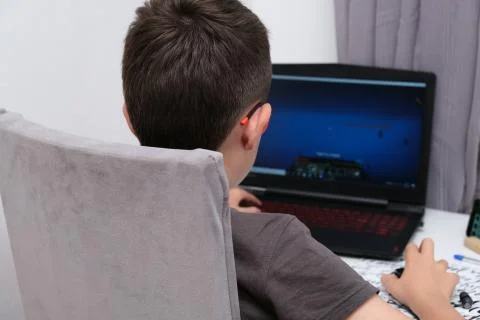 A boy playing online computer game, he is immersed in atmosphere of virtual Stock Photos