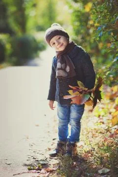Boy playing outdoor with falling leaves in autumn scenery. Stock Photos