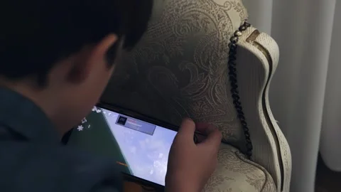 A boy is playing on the phone, a child is playing a game on the phone Stock Footage 260891927