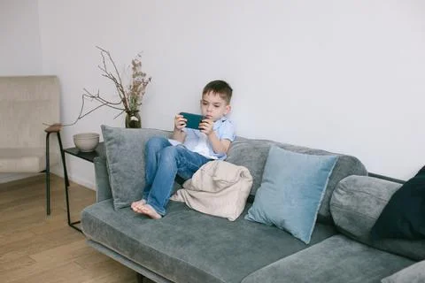 Boy playing phone on the sofa. Stock Photos
