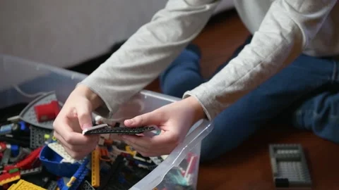 A boy is playing a plastic bricks, sitting on the floor Stock Footage 140030033