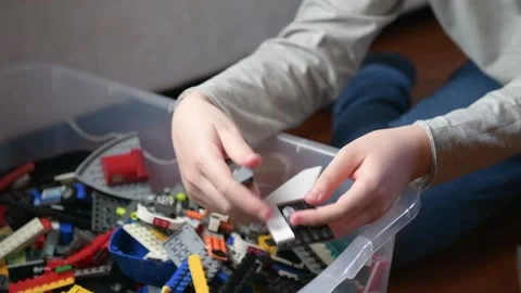 A boy is playing a plastic bricks, sitting on the floor Stock Footage 140030060