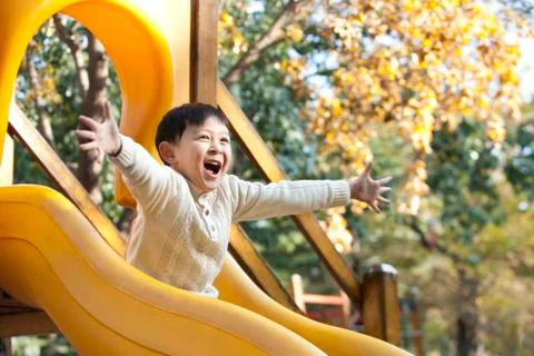 Boy playing on playground slide Foto stock