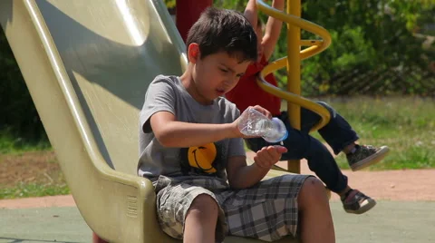 Boy playing on the playground with a water bottle Stock Footage 56156588