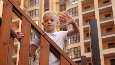 A boy is playing on the playground in the yard, he is standing on a staircase. Stock Footage 314604653