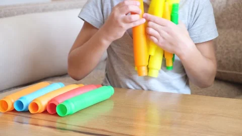 Boy playing with popular sensory plastic toy pop tube. Popular Antistress toy Video stock 166511277