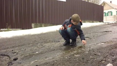 The boy is playing in a puddle. 库存影片 74866427