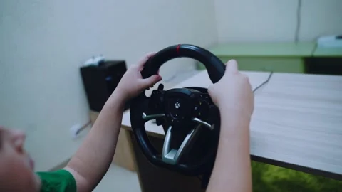 A boy is playing racing on a game console with a steering wheel Stock Footage 167036356