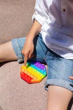 Boy playing with rainbow anti stress pop it toy, outdoors Stock Photos