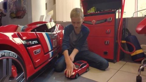 The boy is playing a red car. Video stock 80014602