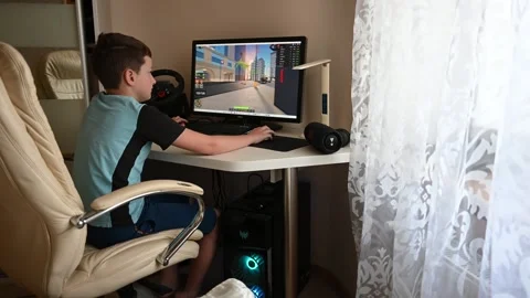 Boy Playing Roblox Video Game on Computer with Steering Wheel at Home Stock Footage 310958048