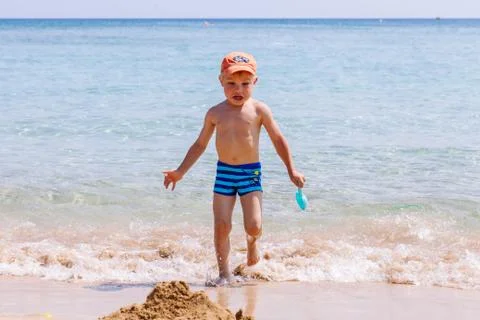 Boy playing in the sand and waves on the beach Stock Photos