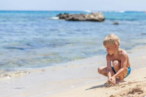 Boy playing in the sand and waves on the beach Stock Photos