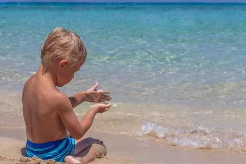 Boy playing in the sand and waves on the beach Stock Photos