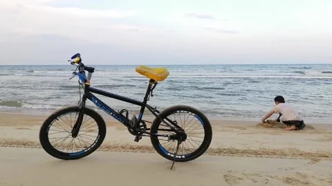 A boy playing sand beach with bicycle background. Stock Footage 161365979