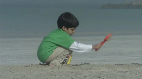 A boy playing with the sand on the beach. Stock Footage 46863593