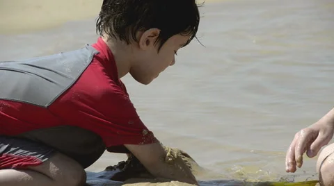 Boy playing with sand on the beach Stock Footage 50554335