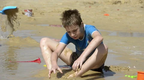 Boy playing with sand on the beach Stock Footage 50555438