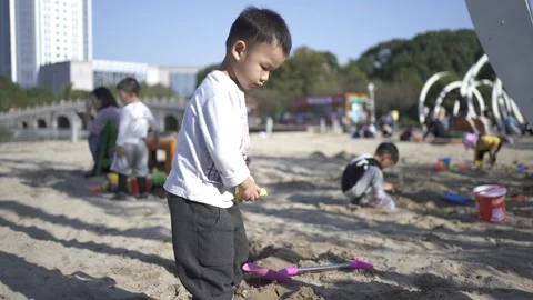 The boy is playing with sand at the beach 스톡 동영상 125357500