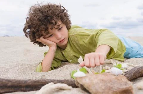 Boy playing with sand on the beach Stock Photos