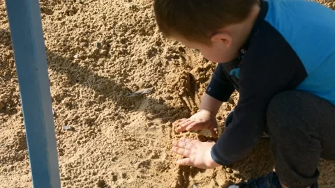 Boy playing with sand in the street 库存影片 153990764