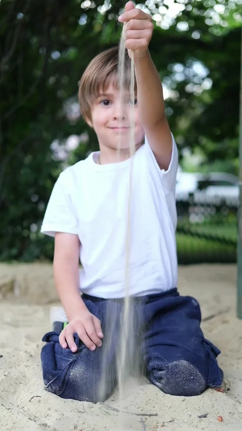 Boy is Playing in Sandpit Playground under the Sun. A little boy sits in a Stock Footage 282787225