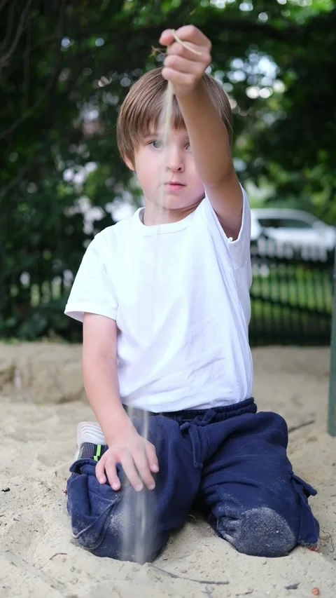 Boy is Playing in Sandpit Playground under the Sun. A little boy sits in a Stock Footage 282788884