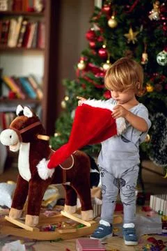 Boy is playing with Santa hat in front of a decorated Christmas tree Stock Photos