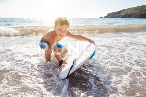 Boy Playing In Sea With Bodyboard On Summer Beach Vacation Stock Photos
