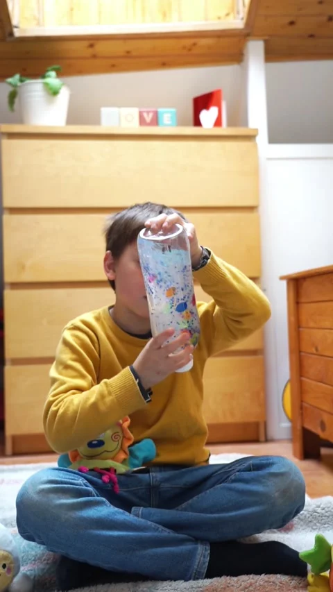 Boy playing with a sensory bottle in his room Stock Footage 267204439