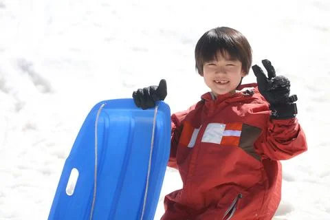 Boy playing with a sled Stock Photos