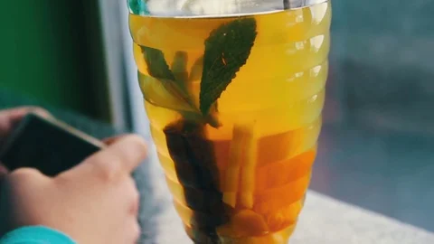 A boy playing on a smartphone in a cafe next to lemon tea with cinnamon Stock Footage