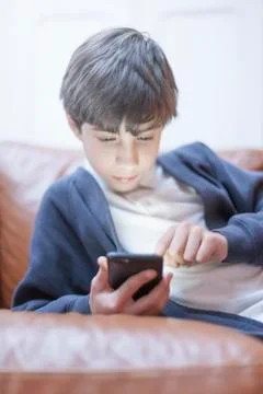 Boy playing with smartphone on sofa Stock Photos