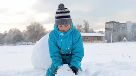 Boy playing in the snow throws a snowball at the camera Stock Footage 148278291