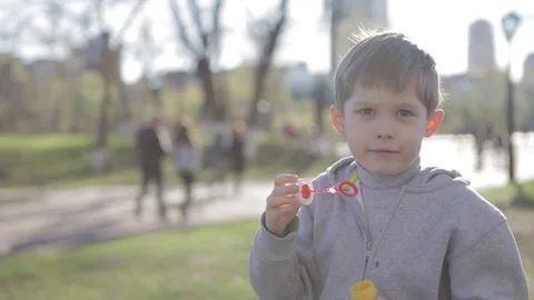 The boy is playing with soap bubbles. A little boy blows bubbles Stock Footage 76615781