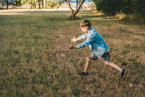 A boy is playing with soap bubbles in a summer park, Among the greenery. Stock Photos