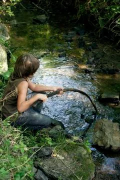 Boy playing with stick in stream Stock Photos