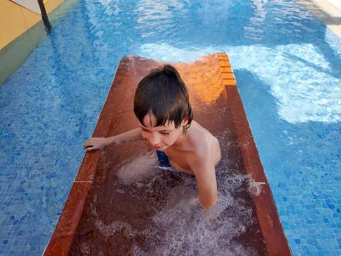 Boy playing in the summer pool Stock Photos