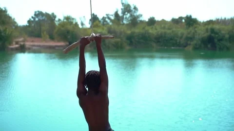 Boy playing with a swing in front of a lake. Stock Footage 323762731