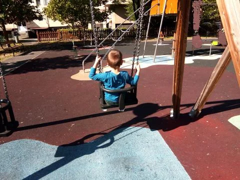 A boy is playing on the swing in the park Фото